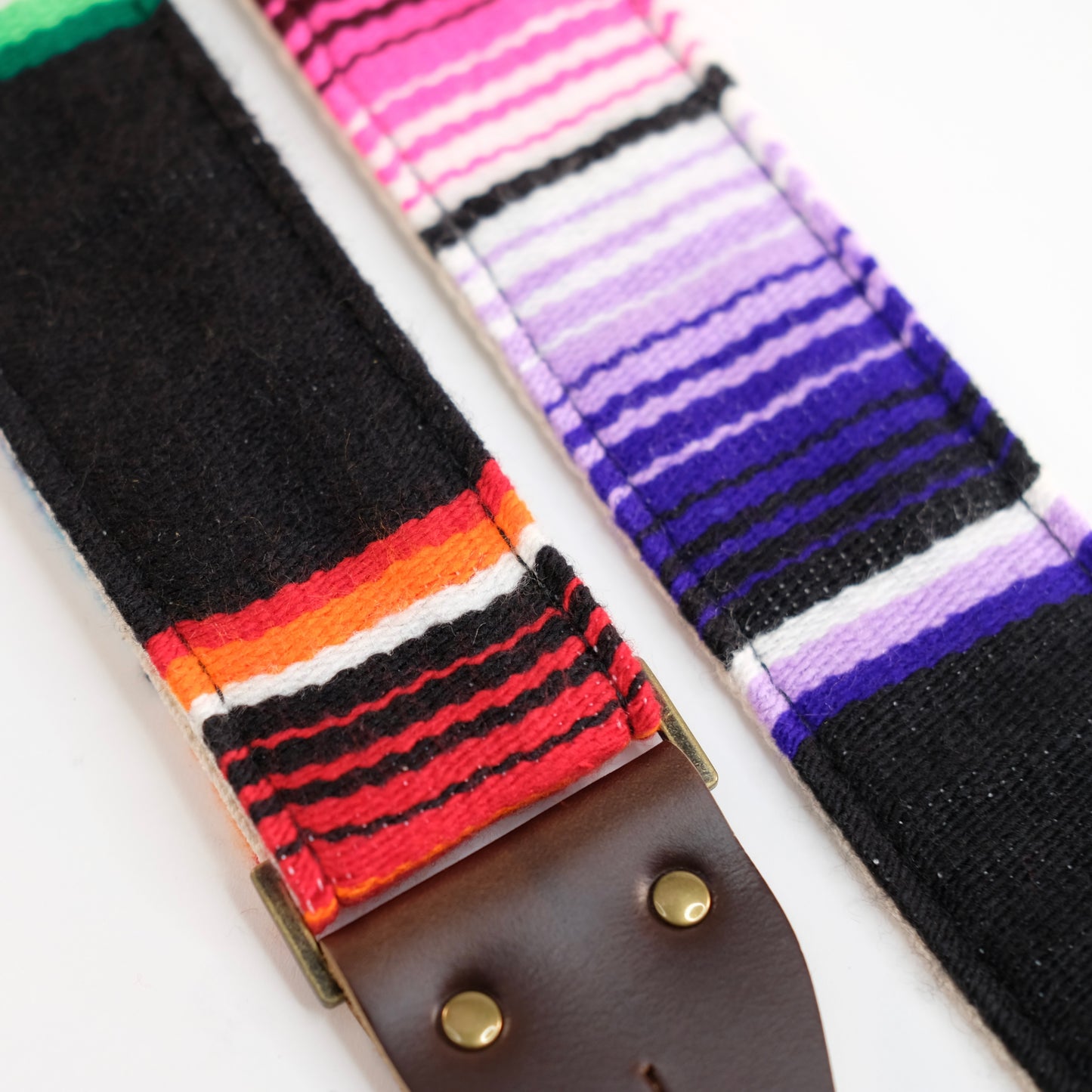 Fabric detail view of guitar strap in black serape fabric with brown leather end-tab. Made in Nashville by Original Fuzz.