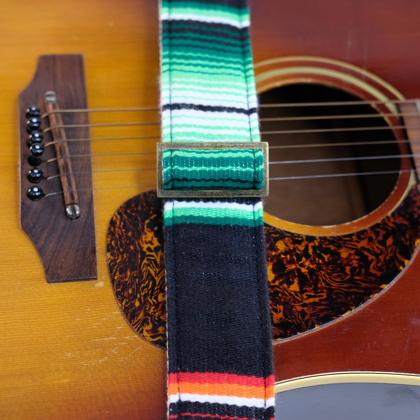 Buckle detail of guitar strap in black serape fabric with brown leather end-tab. Made in Nashville by Original Fuzz.