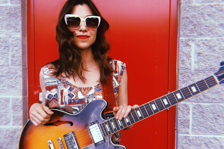 Kristin Reilly, aka Coco Reilly, poses with her guitar and velvet Original Fuzz strap