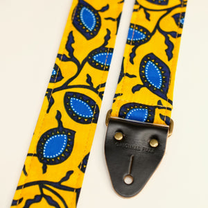 End-tab detail view of guitar strap in yellow and blue botanical African wax print fabric with black leather end-tab. Made in Nashville by Original Fuzz.