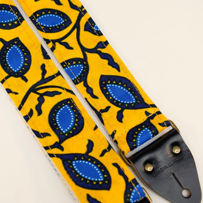 Fabric detail view of guitar strap in yellow and blue botanical African wax print fabric with black leather end-tab. Made in Nashville by Original Fuzz.