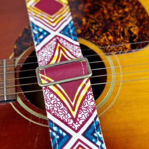 Buckle detail of guitar strap in burgundy, cream, yellow, and dark teal diamond tile African wax print fabric with brown leather end-tab. Made in Nashville by Original Fuzz.