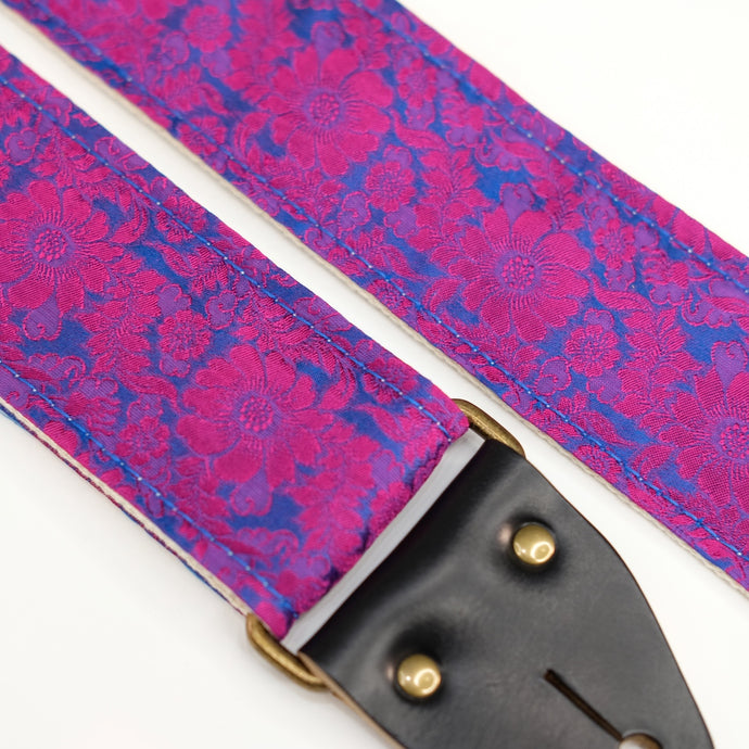 Fabric detail view of guitar strap in pink and blue silk floral fabric with black leather end-tab. Made in Nashville by Original Fuzz.