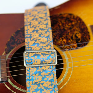 Buckle detail of guitar strap in mustard yellow and teal silk floral fabric with black leather end-tab. Made in Nashville by Original Fuzz.