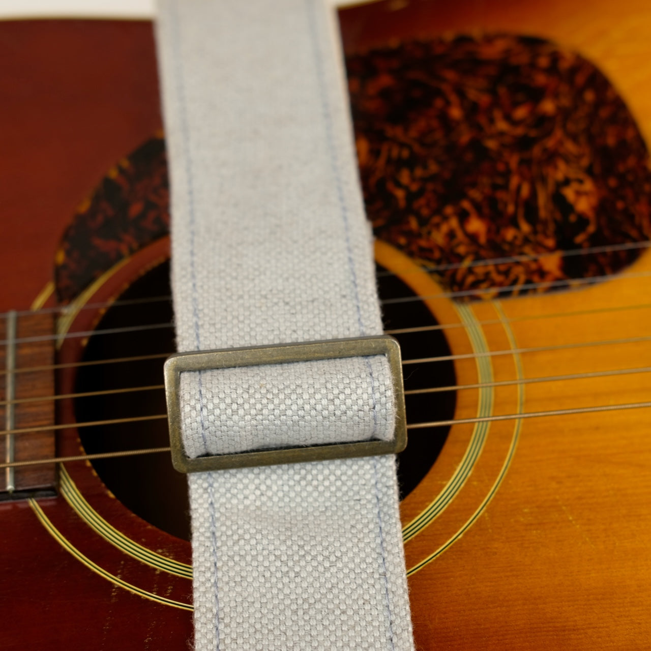 Buckle detail of guitar strap in pale blue-grey woven fabric with brown leather end-tab. Made in Nashville by Original Fuzz.