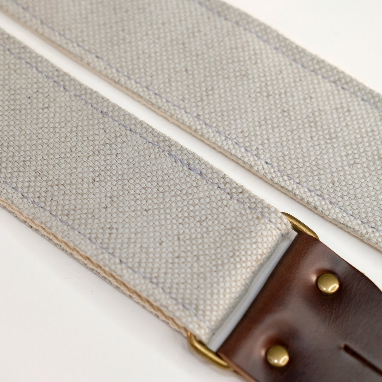 Fabric detail view of guitar strap in pale blue-grey woven fabric with brown leather end-tab. Made in Nashville by Original Fuzz.