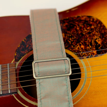 Buckle detail of guitar strap in green-brown silky woven fabric with black leather end-tab. Made in Nashville by Original Fuzz.