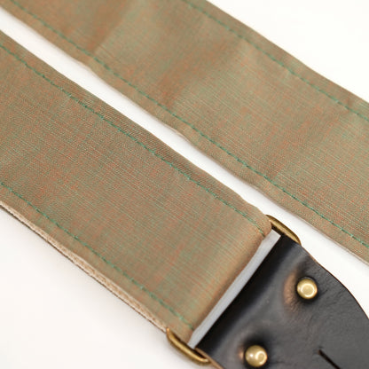 Fabric detail view of guitar strap in green-brown silky woven fabric with black leather end-tab. Made in Nashville by Original Fuzz.