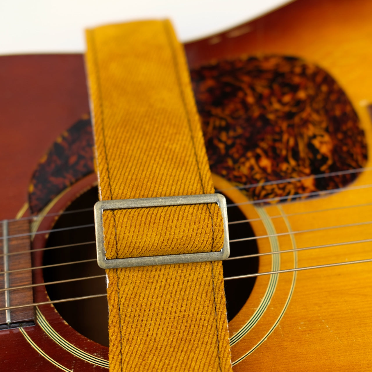 Buckle detail of guitar strap in golden brown woven fabric with black leather end-tab. Made in Nashville by Original Fuzz.