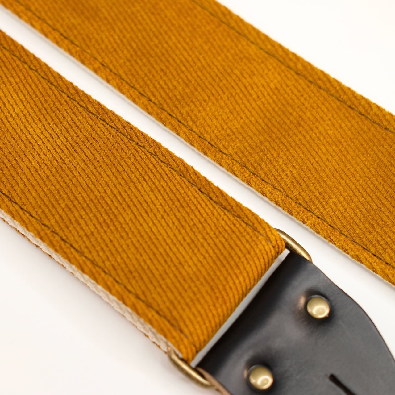 Fabric detail view of guitar strap in golden brown woven fabric with black leather end-tab. Made in Nashville by Original Fuzz.