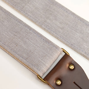 Fabric detail view of guitar strap in cool light grey shimmery woven fabric with brown leather end-tab. Made in Nashville by Original Fuzz.