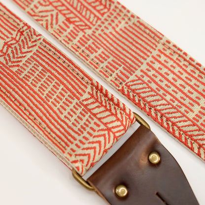 Fabric detail view of guitar strap in beige and red line art woven fabric with brown leather end-tab. Made in Nashville by Original Fuzz.