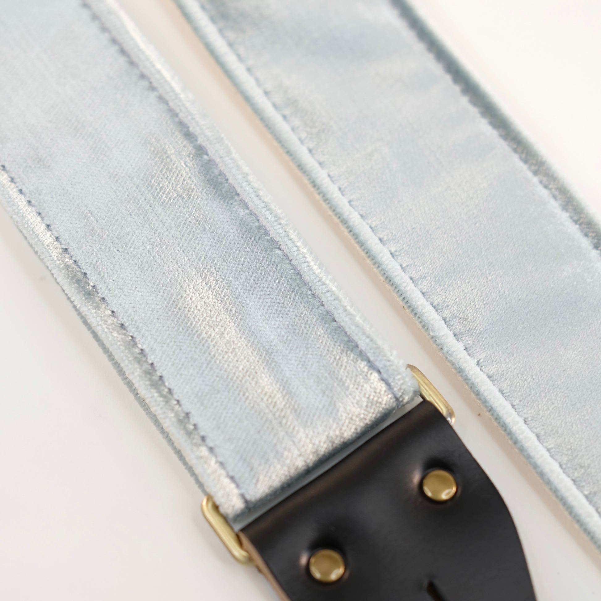 Fabric detail view of guitar strap in pale silver blue velvet with black leather end-tab. Made in Nashville by Original Fuzz.