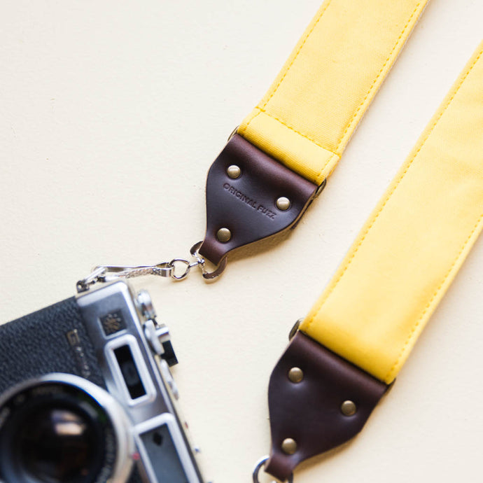 Yellow cotton canvas vintage-style camera strap with antique brass hardware made by Original Fuzz in Nashville, TN with Yashica film camera.