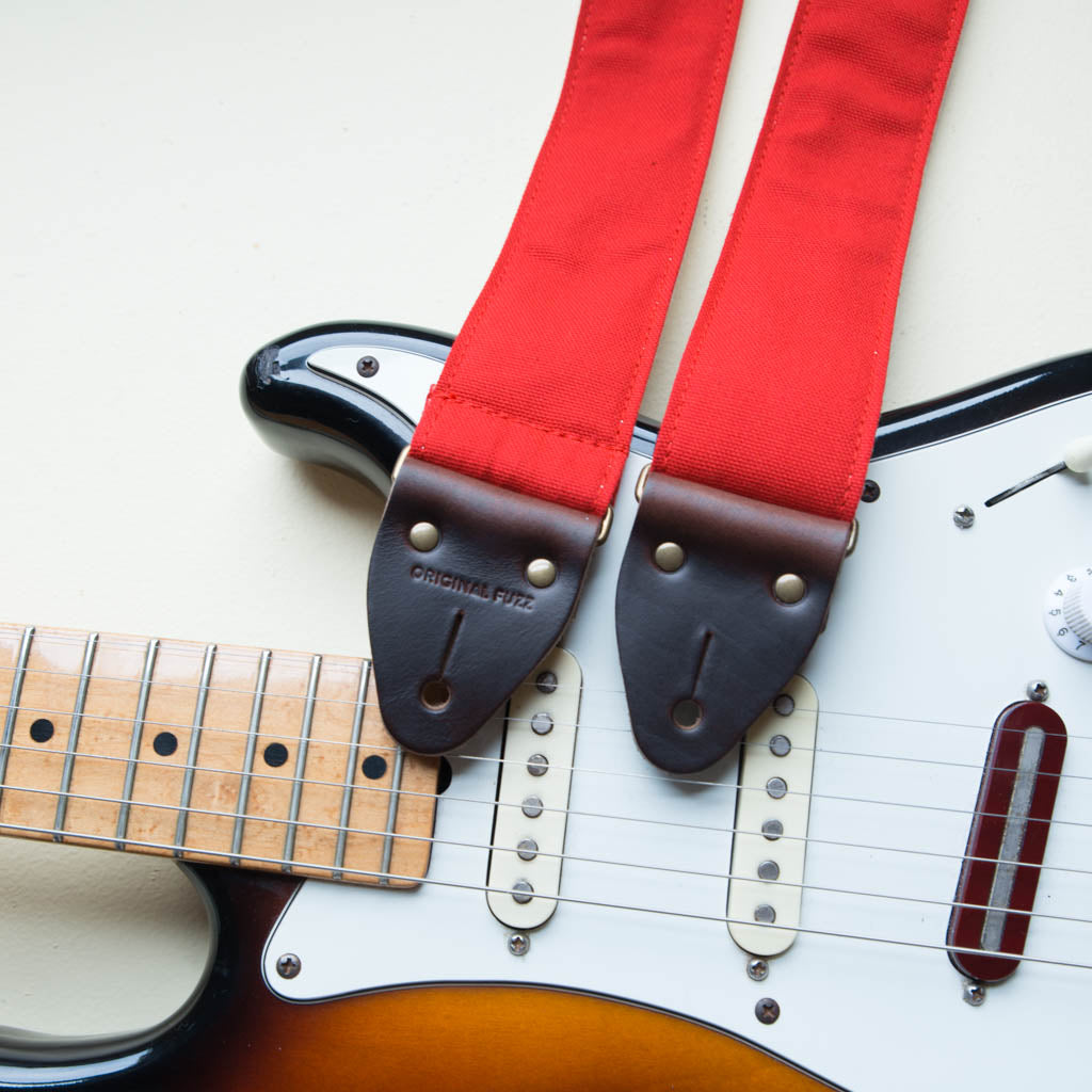 Red cotton canvas vintage-style guitar strap with antique brass hardware made by Original Fuzz in Nashville with a Fender Jazzmaster.