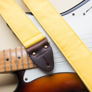 Yellow cotton canvas vintage-style guitar strap with antique brass hardware made by Original Fuzz in Nashville, TN with a Fender Jazzmaster.